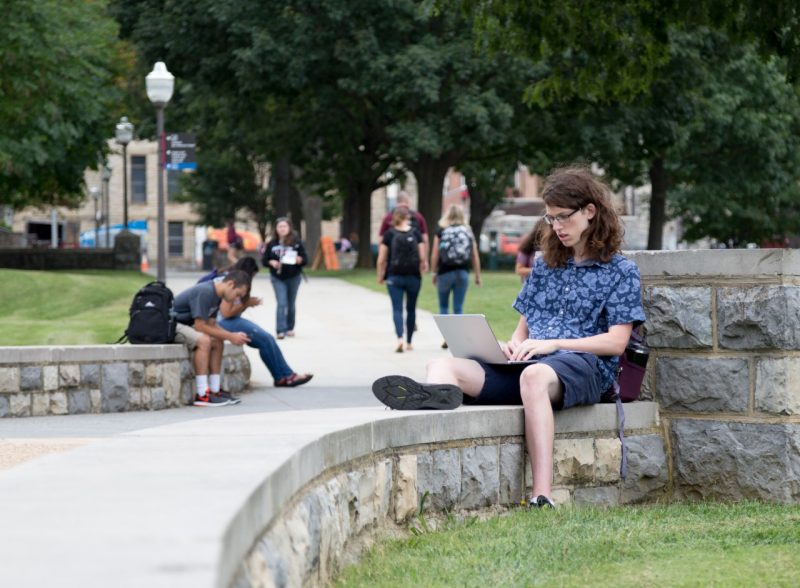 student using laptop outdoors on campus